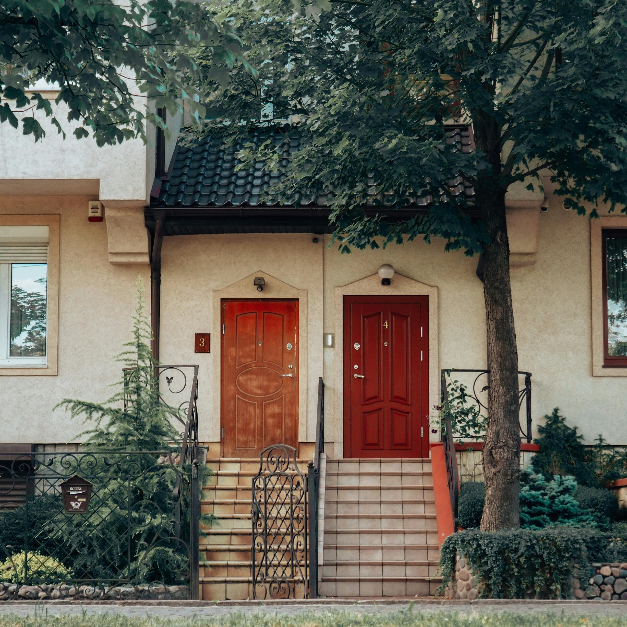 A picturesque view of side-by-side wooden doors framed by greenery in a residential building.
